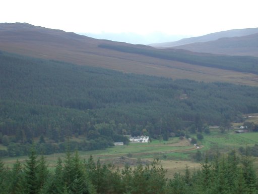 Image:  a long distance shot of a house in the middle of the Scottish Highlands